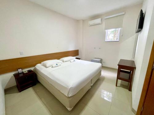 a bedroom with a white bed and a television at Nav Park Hotel in Naviraí