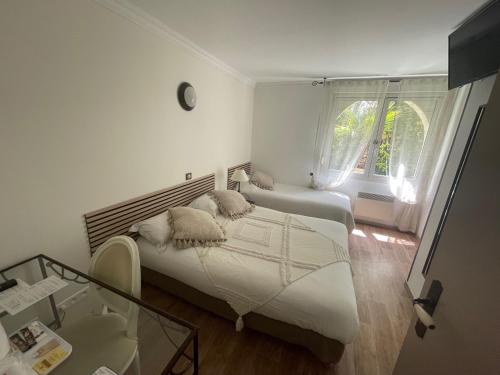 a bedroom with two beds and a glass table at Hôtel Ulysse Montpellier Centre in Montpellier