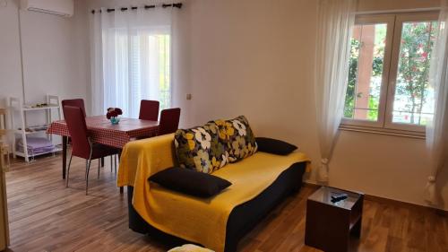 Apartments Ivanovski في راب: غرفة معيشة مع أريكة صفراء وطاولة