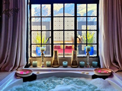 PJURE Wellness Retreat & Spa في مونتاغو: حوض استحمام مع الشموع أمام النافذة