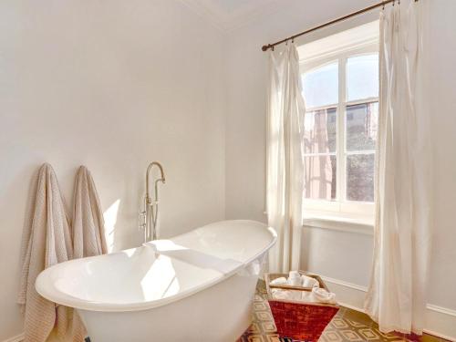 a white bathroom with a tub and a window at Elsewhere on Madison Square Main in Savannah