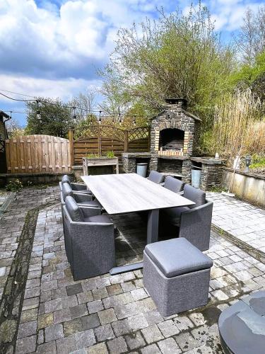 a patio with a table and chairs and a fireplace at La Maison Ardoise in Herbeumont