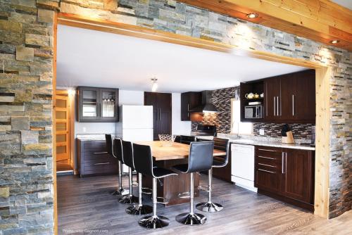a kitchen with a wooden table and black chairs at La Galouine Auberge in Tadoussac