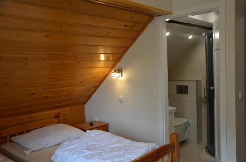 uma cama num quarto com uma parede de madeira em Magurka Rycerka Górna em Rycerka Górna