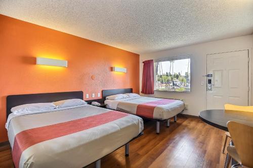 オークランドにあるMotel 6-Oakland, CA - Embarcaderoのベッド2台、テーブル、窓が備わるホテルルームです。