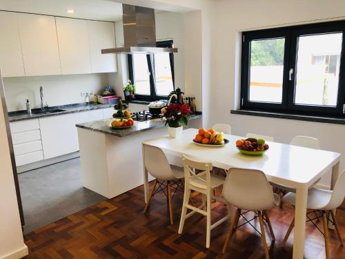 a kitchen with a white table and chairs with fruit on it at Casa em Cascais in Cascais