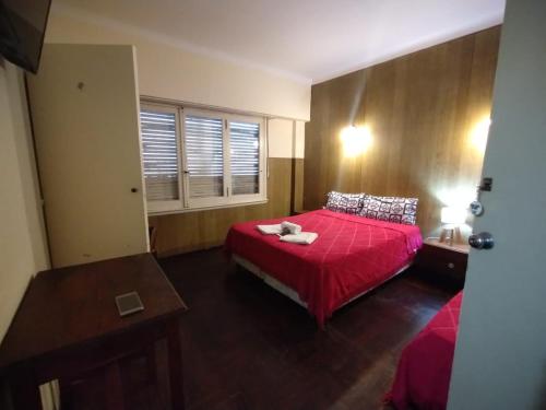 a bedroom with a red bed and a window at Hotel Lobo de Mar - Centro in Mar del Plata