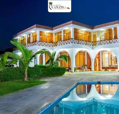 una villa con piscina por la noche en Hotel Cocos Inn, en Ica