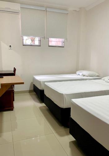 two beds in a room with two windows at Nav Park Hotel in Naviraí