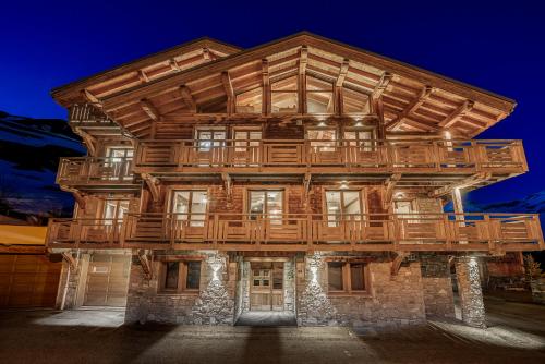 a large wooden building with a deck on top at Chalet ANNAPURNA Lodge GANGA 5 étoiles in Tignes