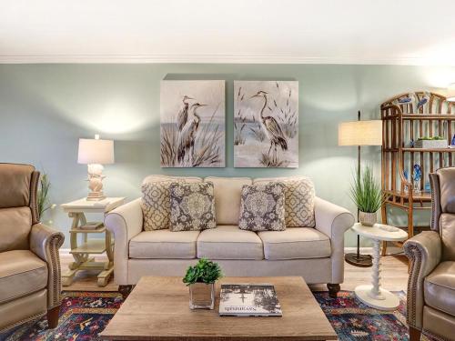 a living room with a couch and paintings on the wall at Stay-A-While in Tybee Island
