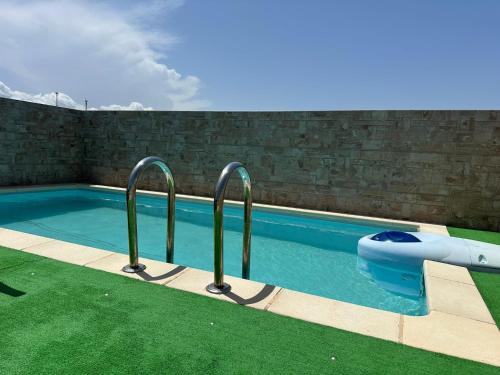 a swimming pool with two metal rails in the grass at Ático con piscina privada vistas al mar. in Vera