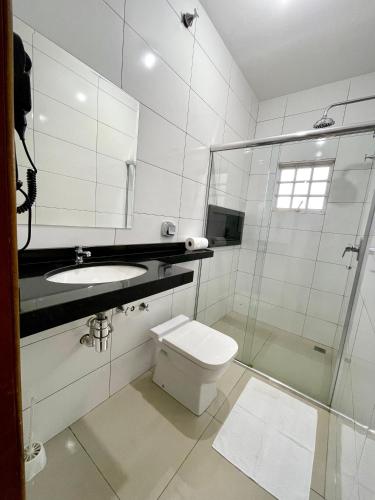 a bathroom with a toilet and a sink and a shower at Nav Park Hotel in Naviraí