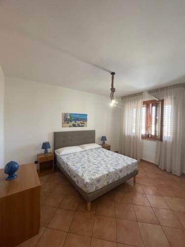 サン・ヴィート・ロ・カーポにあるLe Palme Tropicaliのベッドルーム1室(ベッド1台、ランプ2つ、テーブル付)