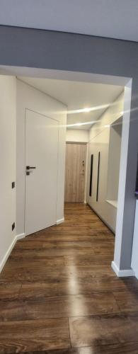 una stanza vuota con pareti bianche e pavimenti in legno di Jaukus 2 kambarių butas Mažeikiuose a Mažeikiai