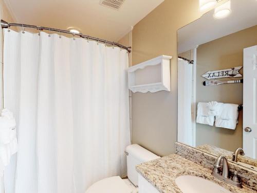 een badkamer met een toilet, een wastafel en een spiegel bij Silver Shores Unit 8 in Tybee Island