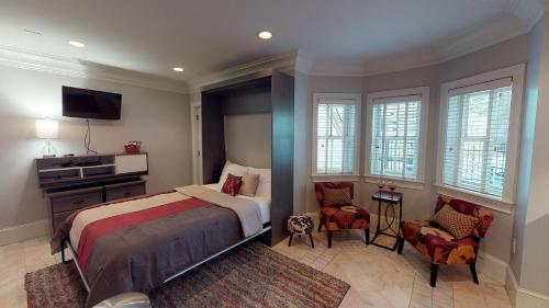 um quarto com uma cama, uma televisão e cadeiras em Suite Escape em Savannah