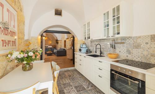 a kitchen with white cabinets and a table with a vase of flowers at Sapir Boutique Apartments in Beer Sheva