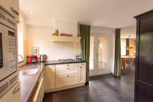 a kitchen with white cabinets and a counter top at Grote vakantiewoning 190m2! op ruim- en groen perceel in Otterlo
