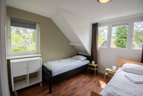 a bedroom with two beds and two windows at Grote vakantiewoning 190m2! op ruim- en groen perceel in Otterlo