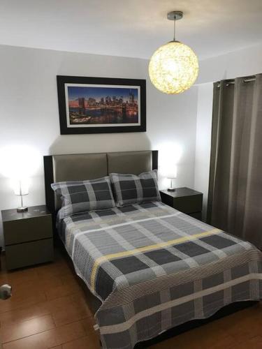 1 dormitorio con 1 cama con manta a cuadros y 2 mesitas de noche en Lindo Departamento en Av. Guardia Civil 861 - Chorrillos, en Lima