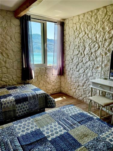 a bedroom with two beds and a stone wall at Hamre Apartments (Nicholas) in Agios Georgios Pagon