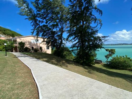 a sidewalk next to a house and the water at Breeze by the sea in Five Islands Village
