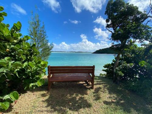 a wooden bench sitting next to the ocean at Breeze by the sea in Five Islands Village