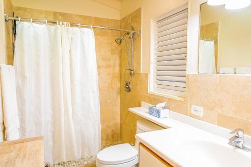 a bathroom with a white shower curtain and a toilet at Breeze by the sea in Five Islands Village