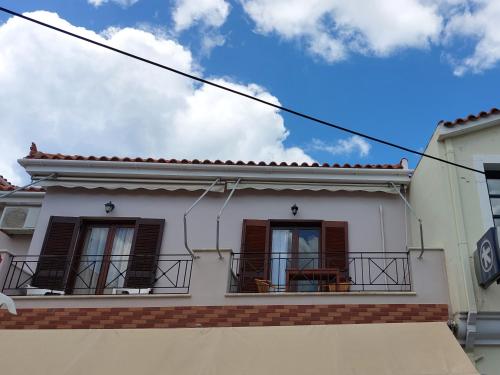 a white house with two windows and a balcony at Theros Apartments in Myrina