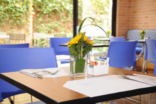 a table with a vase with yellow flowers on it at Mercure Bogota BH Retiro in Bogotá