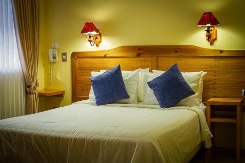 a bedroom with a large bed with blue pillows at Hotel Departamentos del Sur in Puerto Montt