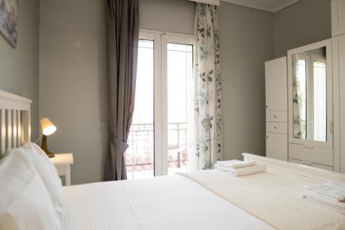 a white bedroom with a bed and a window at Raptis Guest House in Tsilivi