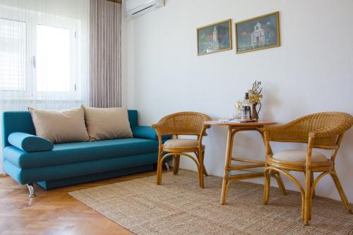 Una sala de estar con un sofá azul y una mesa. en Apartmani Ina Pag, en Pag