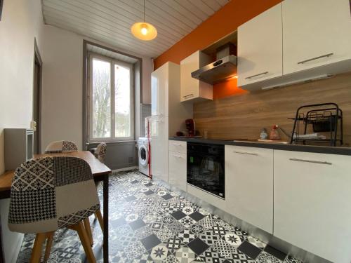 a kitchen with white cabinets and a table and a stove at LE ORANGE - Confort - Wifi - Entre Gare et Centre in Quimper