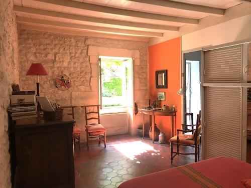 Cette chambre est dotée de murs orange, d'une table et de chaises. dans l'établissement La laiterie du Logis, à Chaniers
