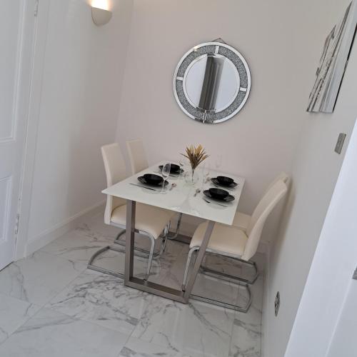 a white dining room table with white chairs and a mirror at Maze 21one Apartment in Ayr