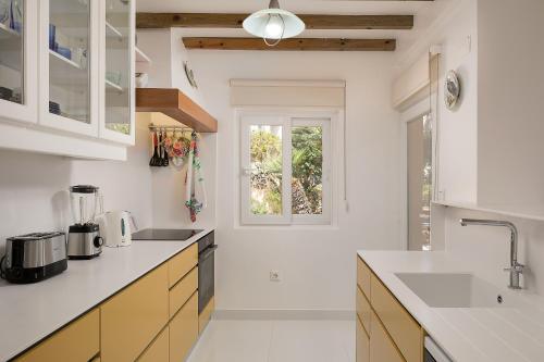 una cocina con encimeras blancas y una ventana en Porto Moniz Villa en Porto Moniz