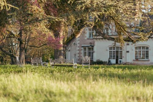 a white house with a tree and chairs in the grass at Château De Razay in Céré-la-Ronde