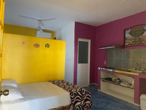 1 dormitorio con cama y pared amarilla y morada en Amanecer, en Sayulita