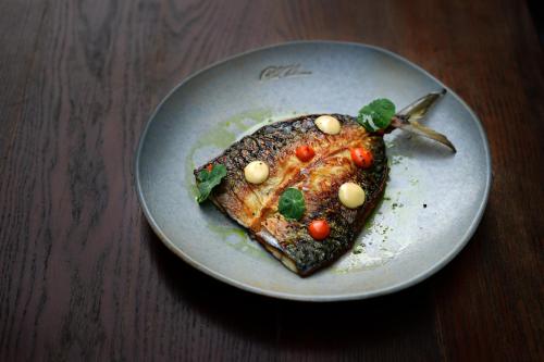 a plate with a piece of fish with tomatoes on it at Pod Zidom Rooms in Zagreb