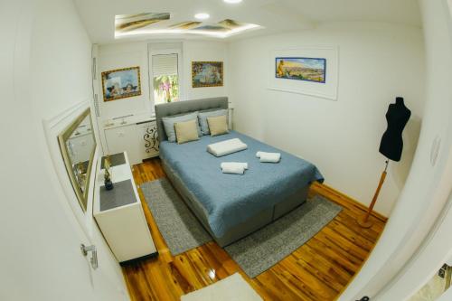ein kleines Schlafzimmer mit einem blauen Bett und Holzböden in der Unterkunft Pahuljica in Čačak