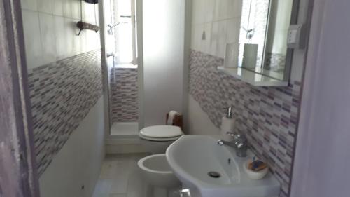 a bathroom with a sink and a toilet and a mirror at Cascina Marasca Appartamento Viola in Martina Olba