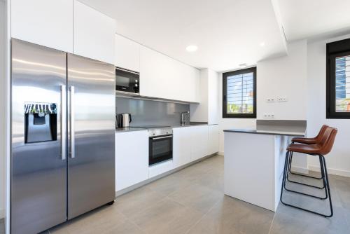 a kitchen with stainless steel refrigerator and white cabinets at Beachfront Apartment 034 in Torre del Mar