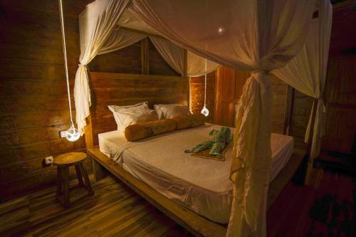 a bedroom with a canopy bed with a stuffed frog on it at Villa Motu Bingin in Uluwatu
