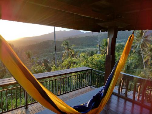 a hammock on a balcony with a view of the mountains at D'kailash Retreat in Singaraja