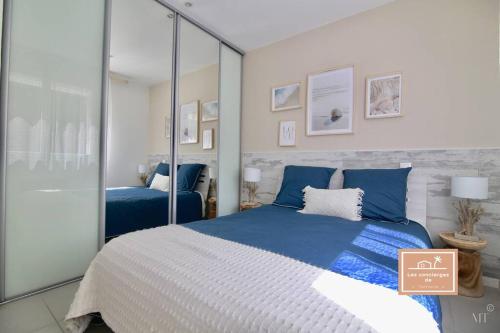 - une chambre avec un lit bleu et blanc et un miroir dans l'établissement Villa Bonheur, à Saint-Mandrier-sur-Mer