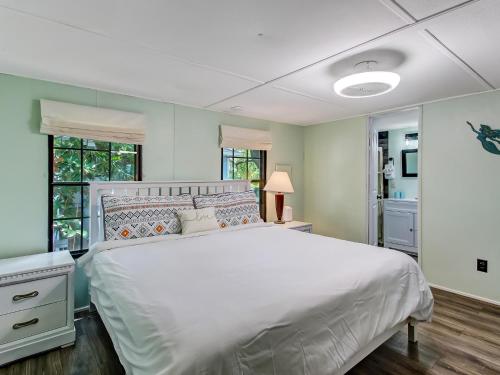 a bedroom with a large white bed and windows at Tybee Tree House in Tybee Island