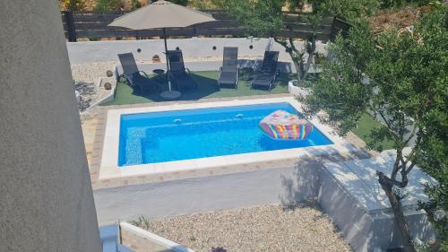 een uitzicht op een zwembad met stoelen en een parasol bij Luxury apartment Duće with private pool in Omiš