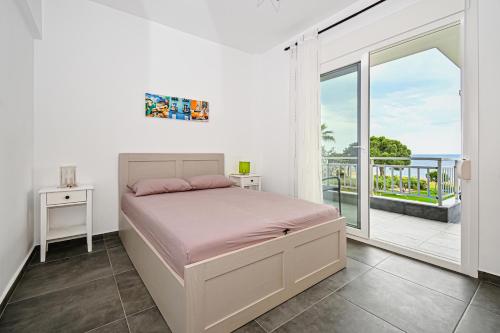 a white bedroom with a bed and a balcony at E & D family apartment by the sea in Kalivia Poligirou